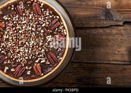 Pecan Pie, made from butter enriched pastry with golden syrup, maple sauce and breadcrumbs, topped with pecans, on dark background Stock Photo