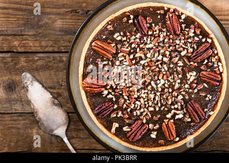 Pecan Pie, made from butter enriched pastry with golden syrup, maple sauce and breadcrumbs, topped with pecans, on dark background Stock Photo