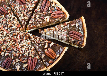 Pecan Pie, made from butter enriched pastry with golden syrup, maple sauce and breadcrumbs, topped with pecans, on dark background Stock Photo