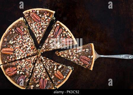 Pecan Pie, made from butter enriched pastry with golden syrup, maple sauce and breadcrumbs, topped with pecans, on dark background Stock Photo