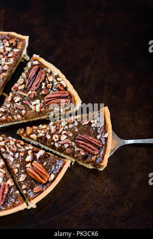 Pecan Pie, made from butter enriched pastry with golden syrup, maple sauce and breadcrumbs, topped with pecans, on dark background Stock Photo