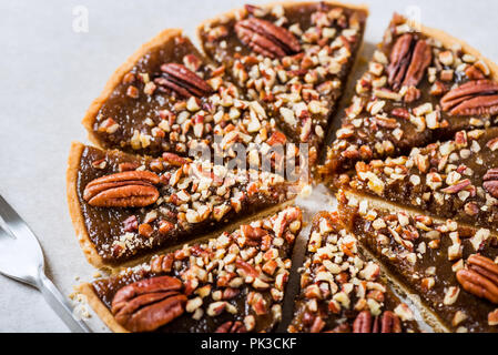 Pecan Pie, made from butter enriched pastry with golden syrup, maple sauce and breadcrumbs, topped with pecans on grey background Stock Photo