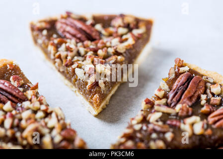 Pecan Pie, made from butter enriched pastry with golden syrup, maple sauce and breadcrumbs, topped with pecans on grey background Stock Photo