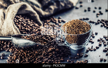 Granules of instant coffee in glass cup and coffee beans. Stock Photo