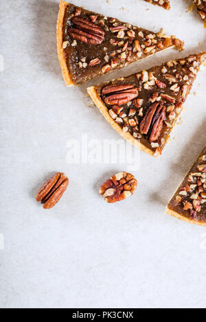 Pecan Pie, made from butter enriched pastry with golden syrup, maple sauce and breadcrumbs, topped with pecans on grey background Stock Photo