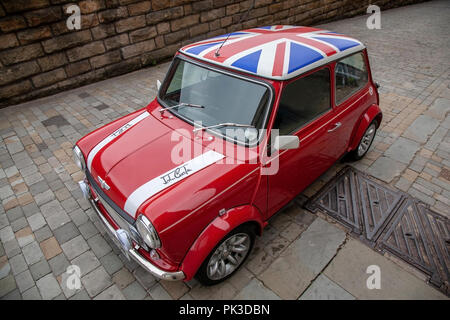 A Red Mini Cooper wth a Union Jack Roof by John Cooper version of the mini parked on a cobbled street in Huddersfield Stock Photo