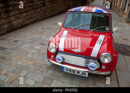 A Red Mini Cooper wth a Union Jack Roof by John Cooper version of the mini parked on a cobbled street in Huddersfield Stock Photo