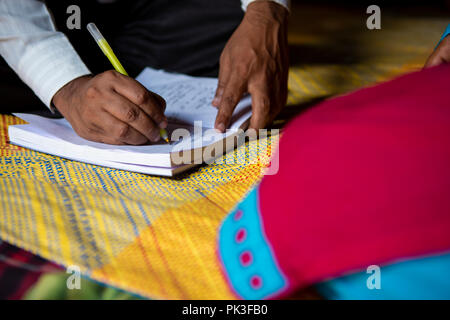 A close up of a man  writing notes in his notebook whilst talking to a woman. Stock Photo