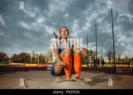 Female athlete performing a long jump during a competition at stadium. The jump, athlete, action, motion, sport, success, championship concept Stock Photo