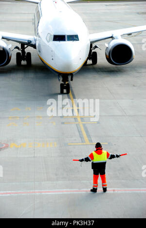 Rear view of ground crew signaling to airplane  to its standing position in the airport Stock Photo