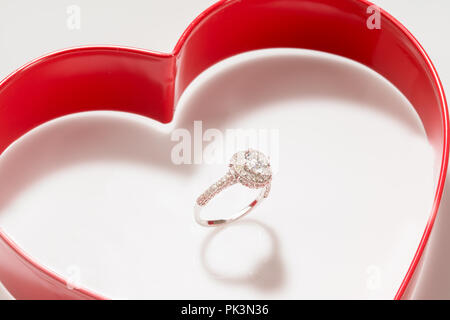 Diamond Ring Set Inside a Red Heart Case on a White Background Stock Photo