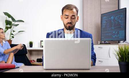 Businessman working at home on the computer while his wife is playing video games in the background Stock Photo