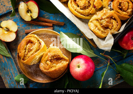 Fresh Homemade Rolls Buns with apples and cinnamon in glaze on a blue vintage wooden background. Top view flat lay background. Stock Photo