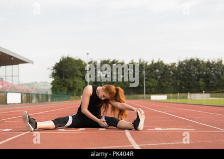 Female athletic exercising on running track Stock Photo