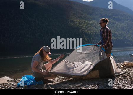 Couple setting up tent near riverside Stock Photo