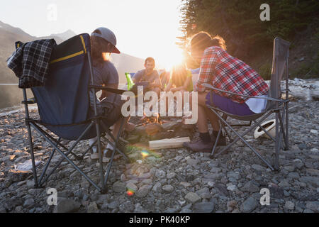 Group of friends roasting hot dogs on campfire Stock Photo