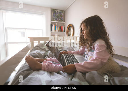 Girl using laptop on bed in bedroom Stock Photo