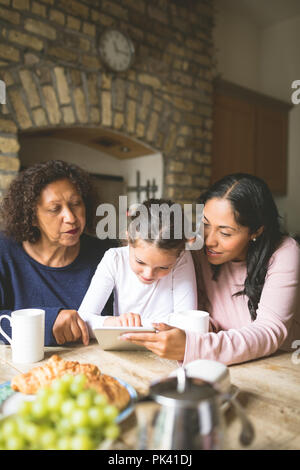 Family using digital tablet on dining table Stock Photo