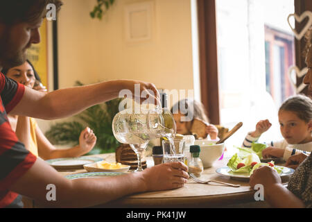 Man serving water in glass on dining table Stock Photo