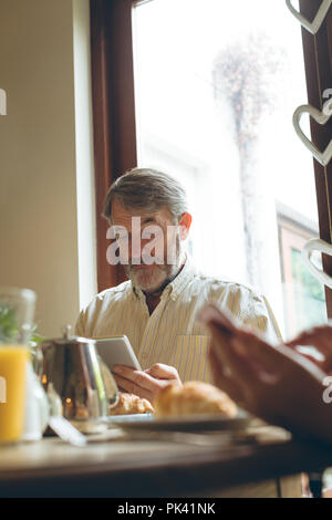 Senior man using digital tablet while having breakfast Stock Photo