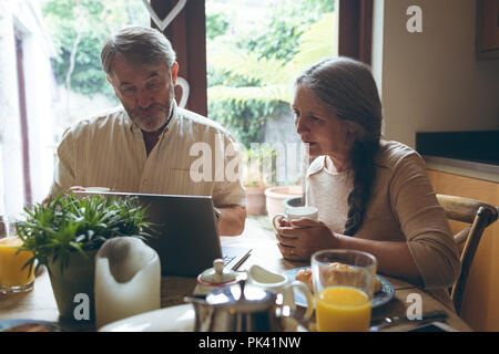 Senior couple using laptop while having coffee Stock Photo