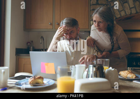 Senior couple using laptop on dining table Stock Photo