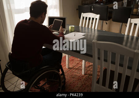 Disabled man using digital tablet on dinning table Stock Photo