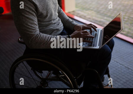 Disabled man using laptop in workshop Stock Photo
