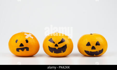 Three Fresh Oranges with Halloween Pumpkins painted face. Easy DIY decoration for Halloween festival isolated on white. Stock Photo