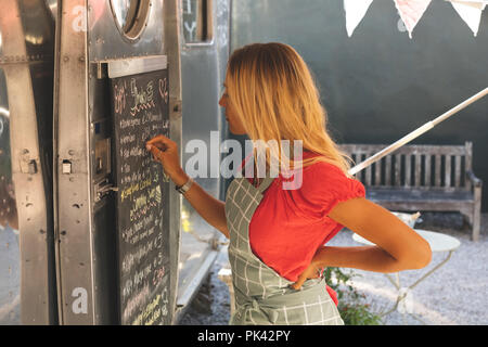 Female waitress writing menu on menu board Stock Photo