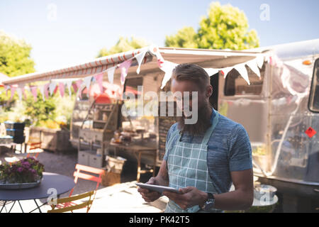 Male waiter using digital tablet near food truck Stock Photo