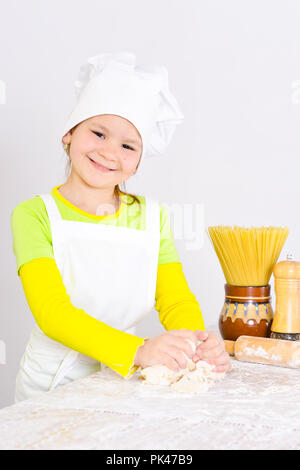 Cute little girl in chef's hat baking cake in the kitchen  Stock Photo