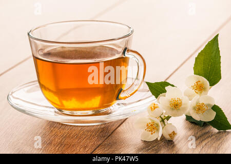 Glass cup of green tea with white jasmine flowers on wooden background Stock Photo