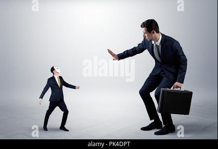 Conflict between small masked businessman and big elegant businessman  Stock Photo