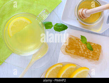 over head colorful shot of honey and lemon hot drink showing honey-cone, blue background fresh lemon slice and mint  copyspace Stock Photo