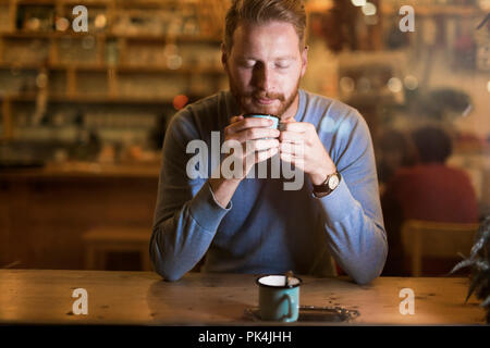 Young handsome man drinking coffee in bar Stock Photo