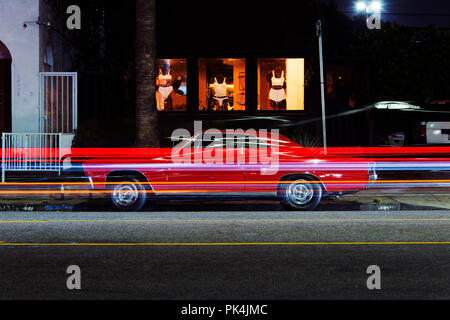 A view of a vintage classic American muscle sports car and light trails by traffic in Venice beach, California at night time Stock Photo