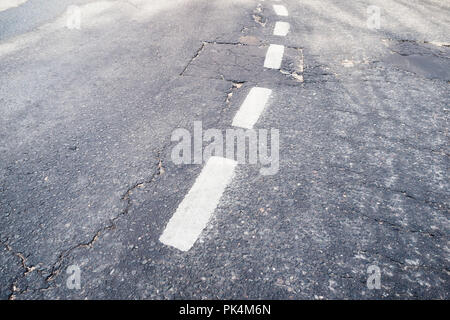broken white separation line on an old asphalt road Stock Photo