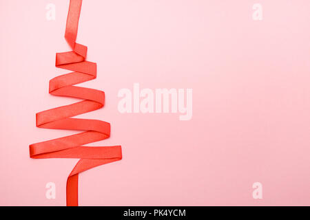 holidays, winter and celebration concept - Christmas and new year tree made from red ribbon on pink background free space for text Stock Photo
