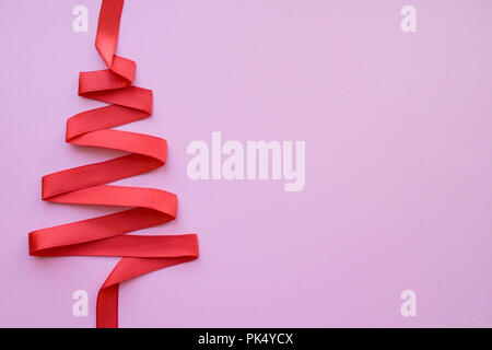 holidays, winter and celebration concept - Christmas and new year tree made from red ribbon on pink background free space for text Stock Photo