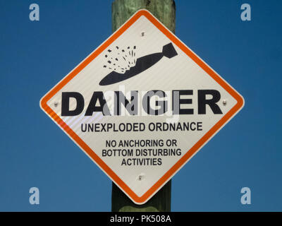 Danger unexploded ordnance bombs sign on a post brilliant blue sky Stock Photo
