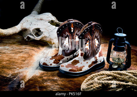 Old West times with cow skull, fancy cowboy boots ,rope and coal oil lantern .. Stock Photo