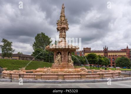 Glasgow, Scotland, UK - June 17, 2012: Doulton Fountain on Glasgow Green under heavy cloudscape. Green foliage and Pendleton building in back. Stock Photo