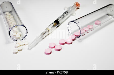 Prescription Pills and Medical needle. Syringe and prescription pills isolated on a white background. White and pink pills. Stock Photo