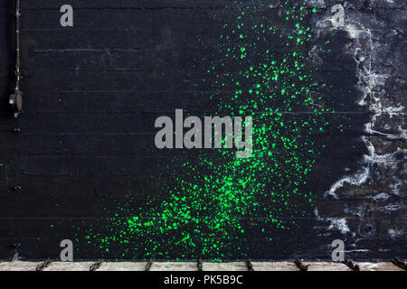 Green pain splatter on black concrete wall Stock Photo