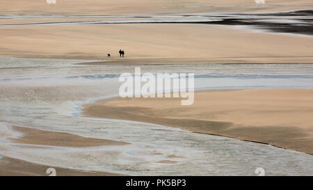 Lone Walkers with dog on Crantock Beach, Cornwall Stock Photo