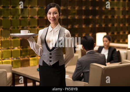Cheerful young waitress serving coffee Stock Photo