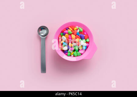 Concept pink plate on pastel pink background food multi-colored metal spoon. Top view flat lay copy space. Stock Photo