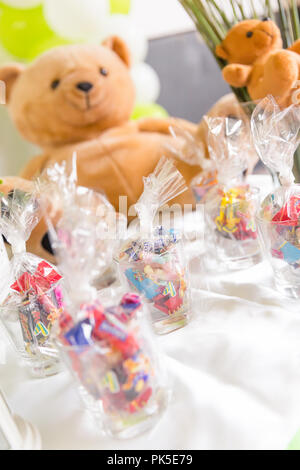 Glasses of Bagged Sweets on White Table with Teddy Bears in Background Stock Photo