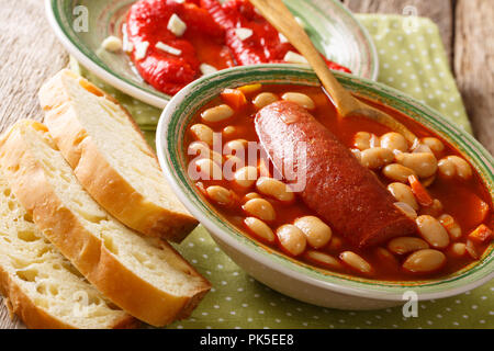 Home-made bean soup with sausage is served with bread and bell pepper close-up on the table. horizontal